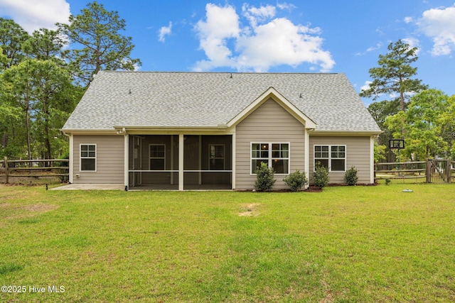 rear view of property with a fenced backyard, a yard, a shingled roof, and a sunroom