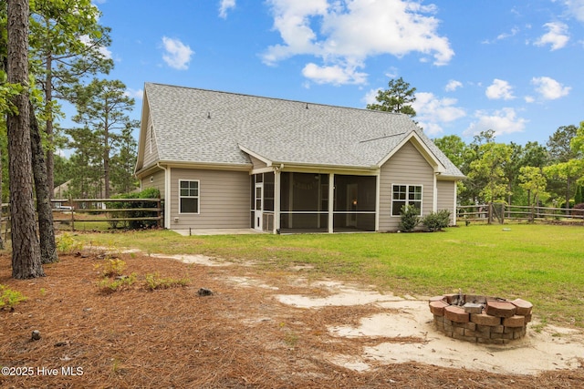 back of house featuring a sunroom, a fenced backyard, a fire pit, and roof with shingles