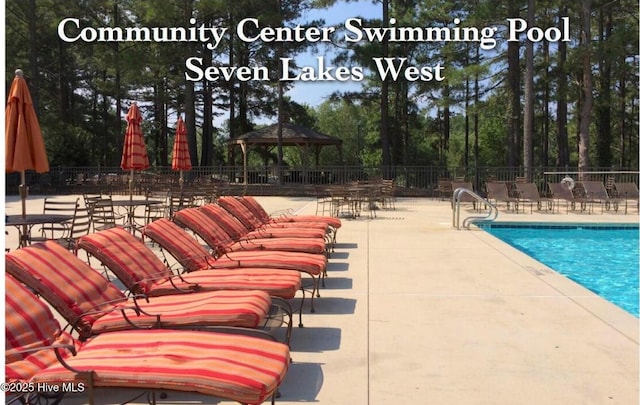community pool with fence, a gazebo, and a patio area