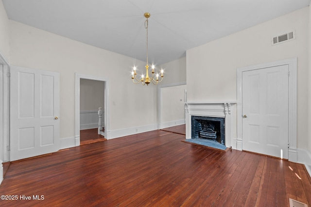 unfurnished living room with hardwood / wood-style floors, visible vents, an inviting chandelier, and a fireplace