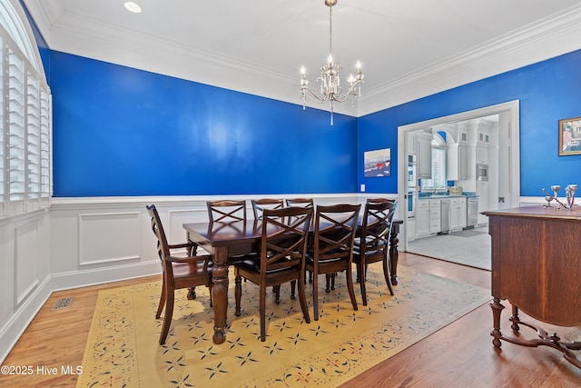 107 Waterway Crossing Ct, Little River, SC 29566 - dining area featuring a chandelier, light wood-type flooring, ornamental molding, and a wainscoted wall