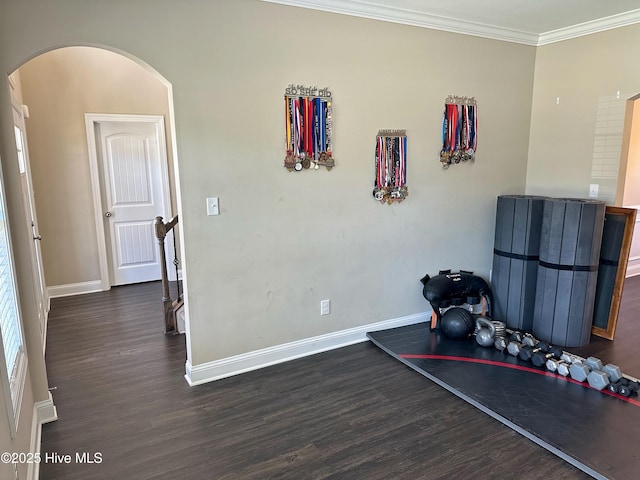 exercise room with dark wood-style flooring, baseboards, ornamental molding, and arched walkways