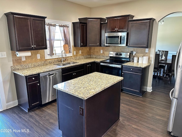 kitchen featuring a sink, appliances with stainless steel finishes, dark brown cabinets, baseboards, and dark wood-style flooring