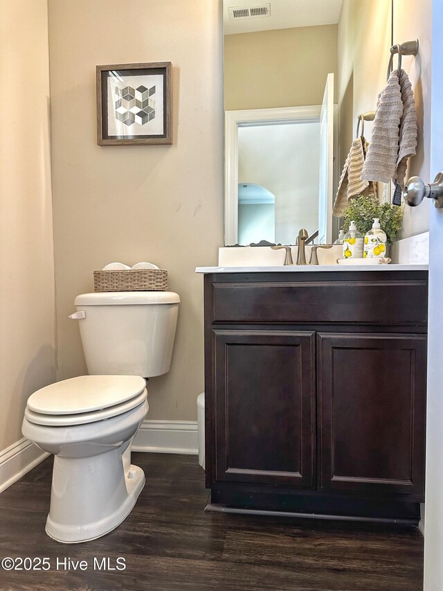 bathroom featuring vanity, toilet, visible vents, baseboards, and wood finished floors