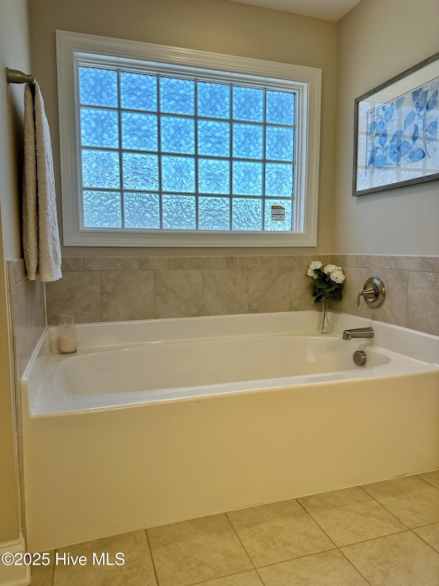 bathroom with a garden tub and tile patterned floors