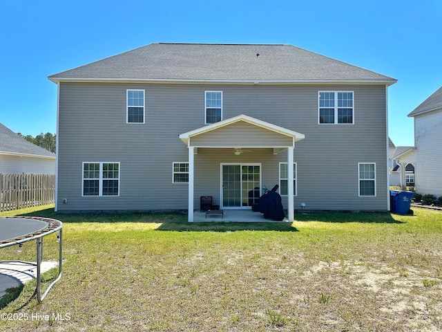 back of house featuring a trampoline, a yard, fence, a patio area, and a ceiling fan