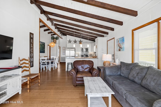 living room featuring lofted ceiling with beams, visible vents, and light wood-type flooring