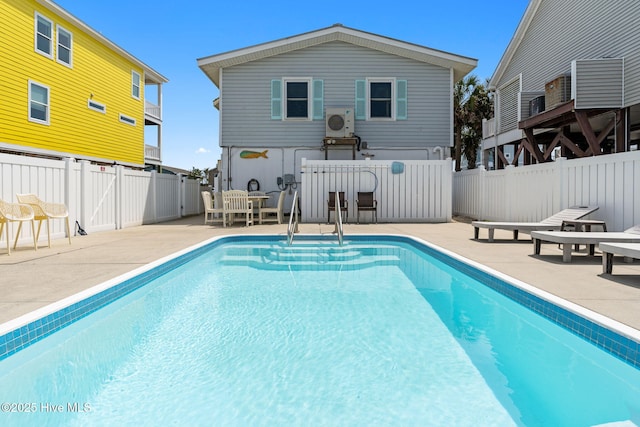back of house featuring a fenced backyard, a fenced in pool, and a patio area