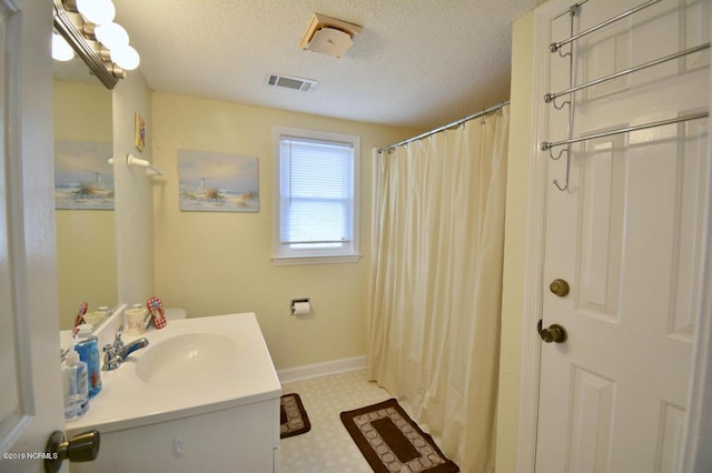 bathroom with visible vents, vanity, baseboards, a textured ceiling, and tile patterned floors
