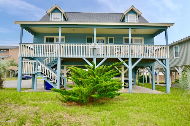 rear view of house featuring a porch, a shingled roof, and a yard