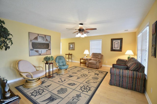 living area featuring baseboards, a ceiling fan, and wood finished floors
