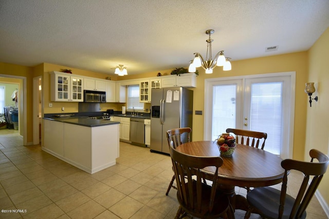 kitchen featuring dark countertops, an inviting chandelier, stainless steel appliances, light tile patterned floors, and visible vents