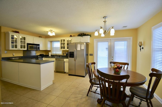 kitchen with appliances with stainless steel finishes, a sink, a chandelier, a peninsula, and visible vents
