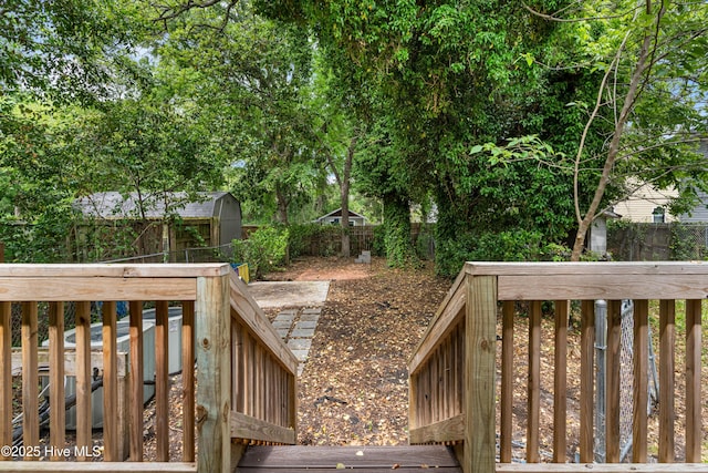 deck featuring an outdoor structure, a storage unit, and a fenced backyard