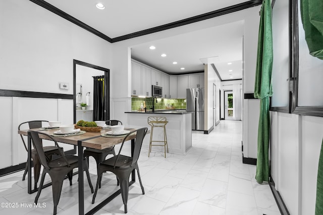 dining room with recessed lighting, marble finish floor, a decorative wall, ornamental molding, and wainscoting