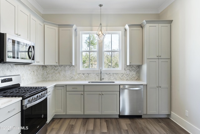 kitchen featuring appliances with stainless steel finishes, tasteful backsplash, a sink, light countertops, and dark wood-style floors