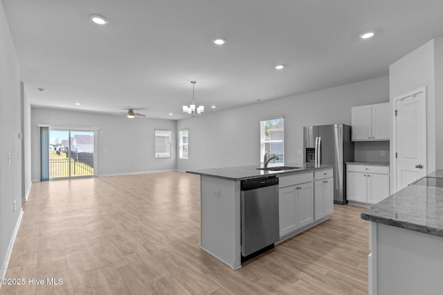 kitchen with a healthy amount of sunlight, white cabinets, a sink, dark stone countertops, and stainless steel appliances