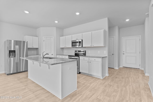 kitchen with white cabinets, appliances with stainless steel finishes, a sink, and light wood-style flooring