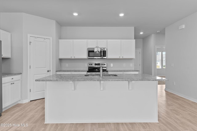kitchen with light wood-style flooring, white cabinets, and stainless steel appliances