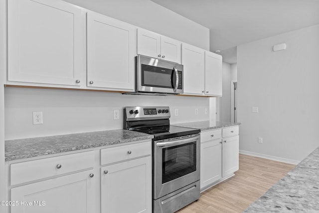 kitchen featuring light stone countertops, light wood-style floors, baseboards, white cabinetry, and appliances with stainless steel finishes