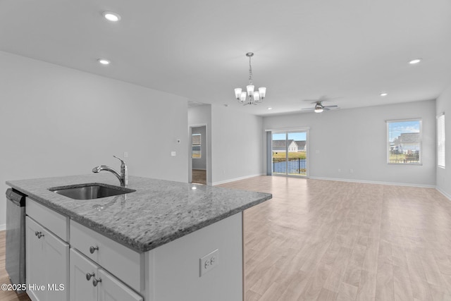 kitchen with hanging light fixtures, a sink, dishwasher, light wood-style flooring, and ceiling fan with notable chandelier