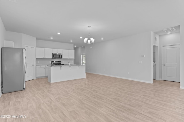 kitchen with appliances with stainless steel finishes, a chandelier, white cabinetry, open floor plan, and recessed lighting