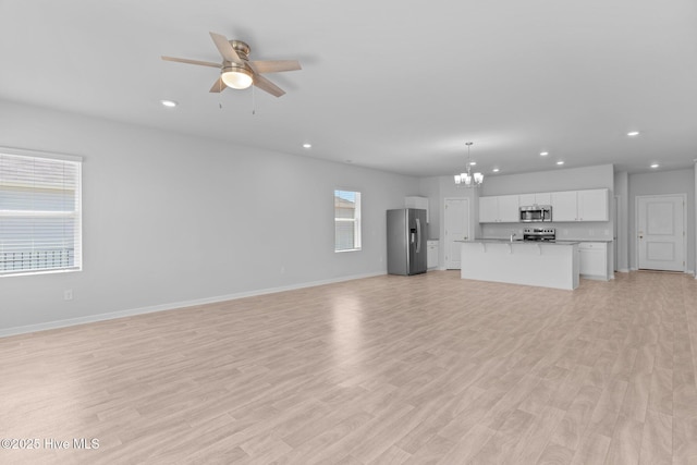 unfurnished living room with recessed lighting, baseboards, and ceiling fan with notable chandelier