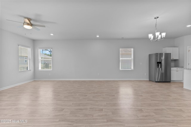 unfurnished living room with light wood-style floors, baseboards, ceiling fan with notable chandelier, and recessed lighting
