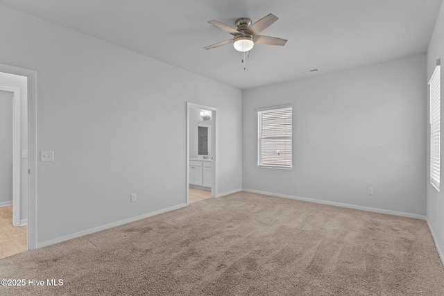 empty room featuring a ceiling fan, light colored carpet, and a wealth of natural light