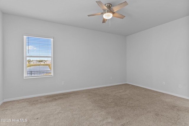 carpeted empty room with baseboards and a ceiling fan