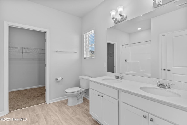 bathroom featuring a sink, toilet, wood finished floors, a shower, and visible vents