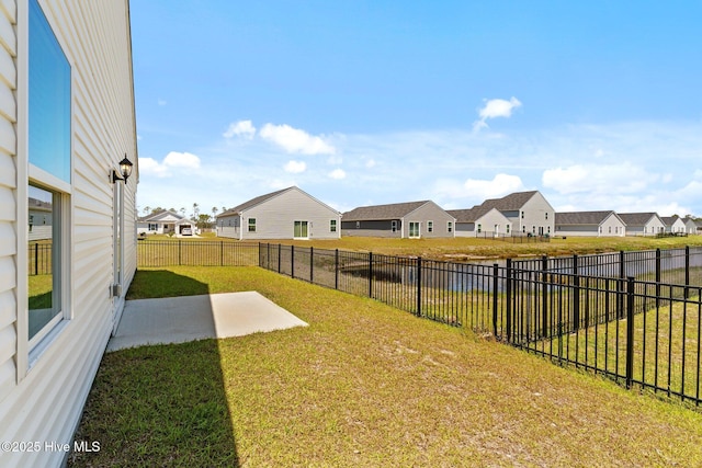 view of yard with a patio, a water view, a residential view, and a fenced backyard