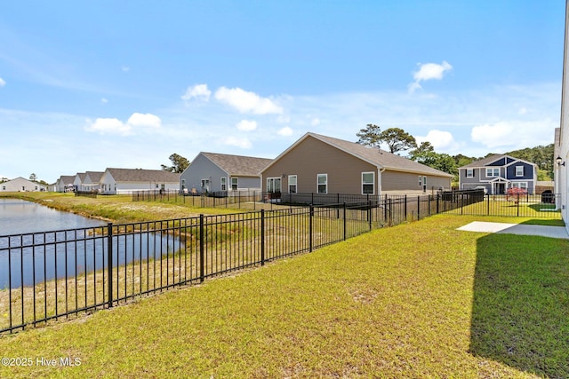 view of yard featuring a water view, fence, and a residential view