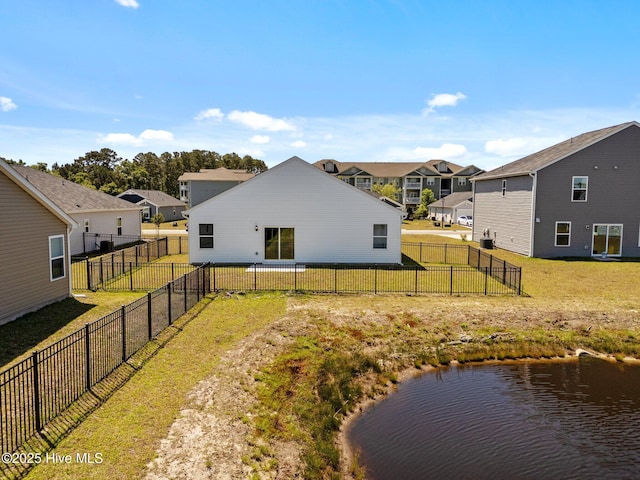 rear view of house featuring a residential view, a water view, a lawn, and a fenced backyard