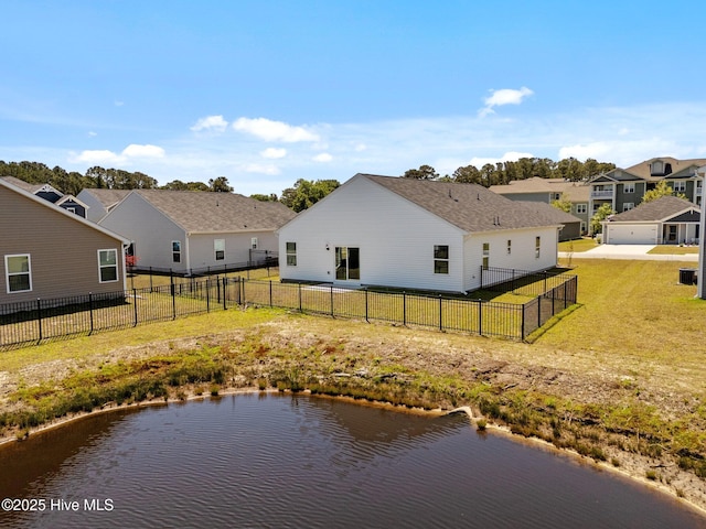 rear view of house with a residential view, a water view, a lawn, and a fenced backyard
