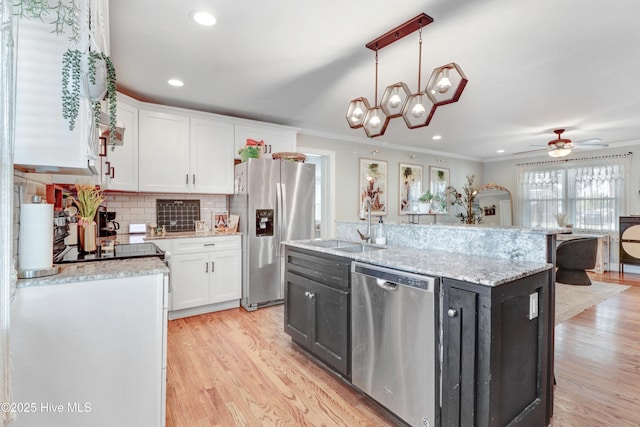 kitchen with white cabinets, stainless steel appliances, light wood-style flooring, and an island with sink