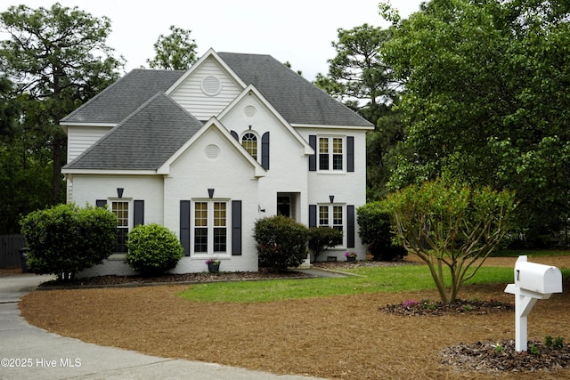 view of front of property with brick siding, a shingled roof, and a front yard