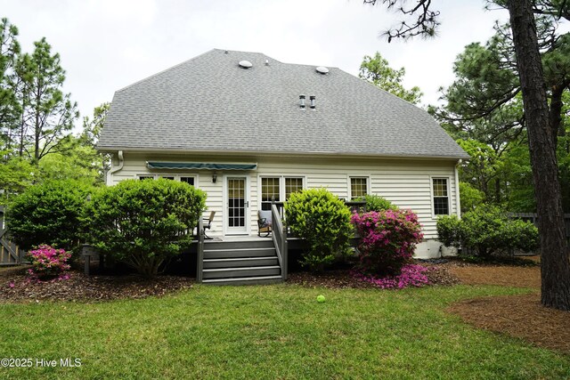 back of property featuring roof with shingles, a wooden deck, and a yard