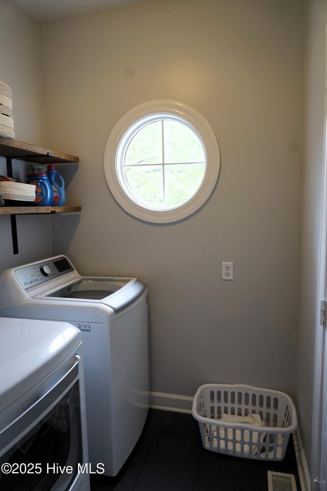 washroom featuring dark tile patterned floors, laundry area, visible vents, baseboards, and separate washer and dryer
