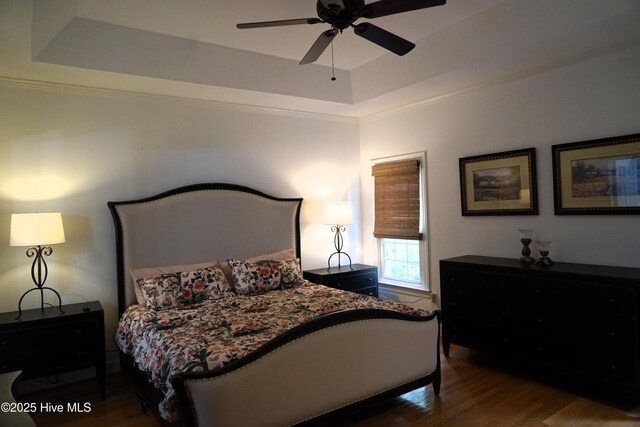 bedroom featuring crown molding, a ceiling fan, wood finished floors, and a tray ceiling