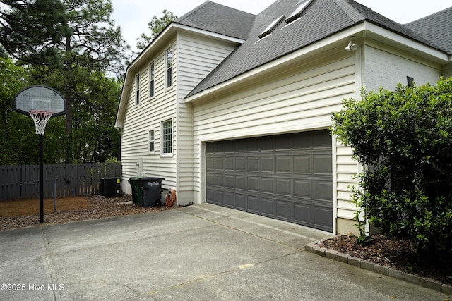 view of home's exterior with concrete driveway, central AC, fence, and a shingled roof