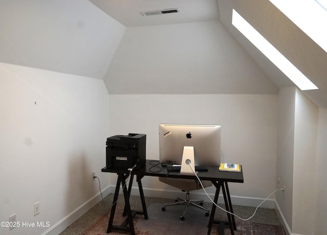 office area with visible vents, carpet flooring, baseboards, and vaulted ceiling with skylight