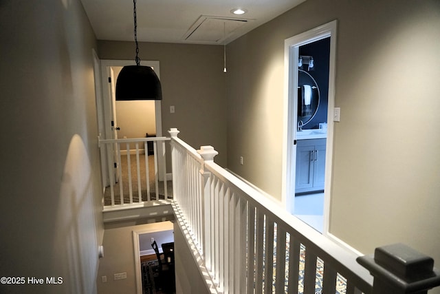 hallway featuring an upstairs landing, a sink, and attic access