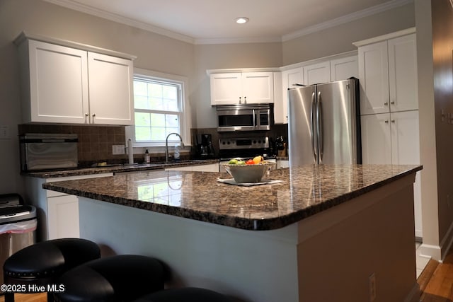 kitchen featuring a sink, decorative backsplash, white cabinetry, and stainless steel appliances