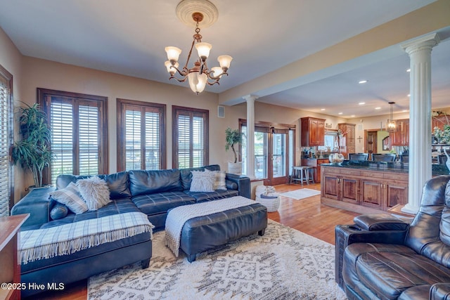 753 S Horsepen Dr, Harrells, NC 28444 - living room with light wood-style flooring, decorative columns, a wealth of natural light, and an inviting chandelier