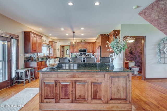 753 S Horsepen Dr, Harrells, NC 28444 - kitchen with light wood finished floors, stainless steel microwave, dark stone countertops, and fridge