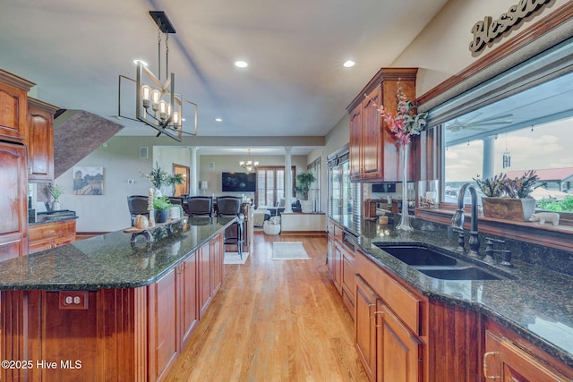 753 S Horsepen Dr, Harrells, NC 28444 - kitchen with hanging light fixtures, light wood-type flooring, a sink, dark stone countertops, and an inviting chandelier