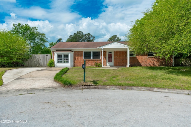 ranch-style home featuring a front yard, driveway, brick siding, and fence