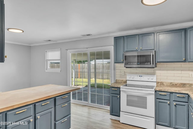 kitchen with wood counters, stainless steel microwave, crown molding, white electric stove, and backsplash