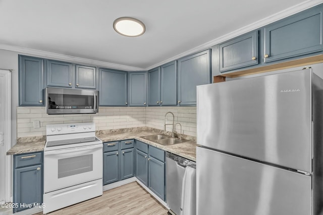 kitchen with appliances with stainless steel finishes, tasteful backsplash, blue cabinets, and a sink